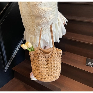Detail of hollow woven pattern on beige straw tote bag with round braided handles