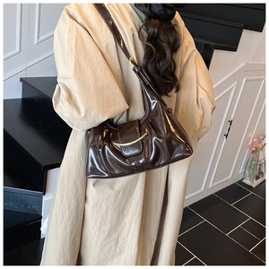 Détail du sac hobo en cuir verni marron foncé avec garniture dorée et plis