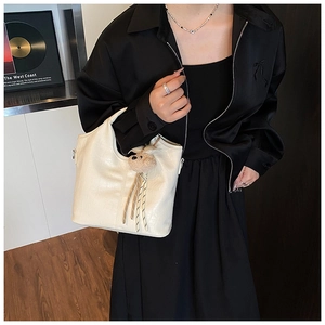 Detail view of cream white faux leather bucket bag with crocodile pattern and bear charm