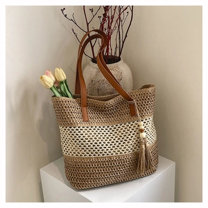 Dettaglio della borsa tote in paglia con manici in pelle marrone e nappa con perle di legno