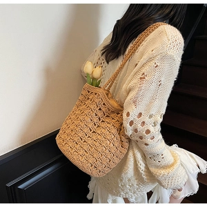 Detail of hand-woven hollow straw shoulder bag styled with tulips and a white knit sweater