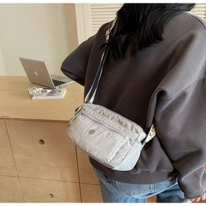 Macro detail of the grey nylon crossbody bag with side zip pocket and patterned strap