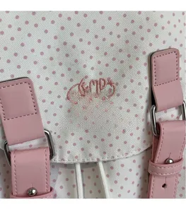 Detailansicht der rosa Lederriemen mit Nieten und Hello-Stickerei auf dem Polka-Dot-Rucksack