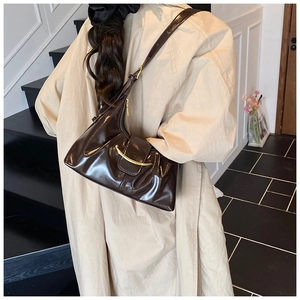 Détail du sac hobo en cuir brillant marron foncé avec un fermoir en métal doré chic