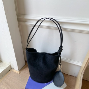 Detail of minimalist black suede bucket bag with long strap and detachable round coin purse