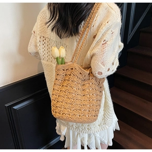 Straw shoulder bag worn by model featuring hollow-out woven texture and yellow tulips