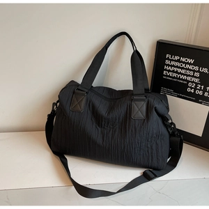 Detail view of large black nylon tote bag with unique crinkled texture and leather accents