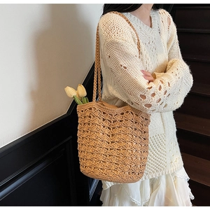 Detailed close-up of handmade hollow floral crochet straw bucket bag with delicate straps