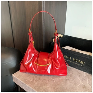 Détail du sac à main en cuir verni rouge vif avec garniture métallique dorée sur le rabat