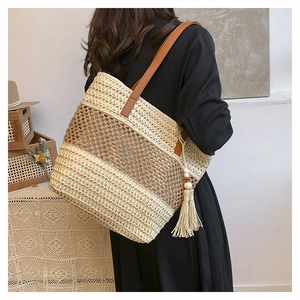 Dettaglio della borsa tote in paglia intrecciata con trama a righe e nappe in legno