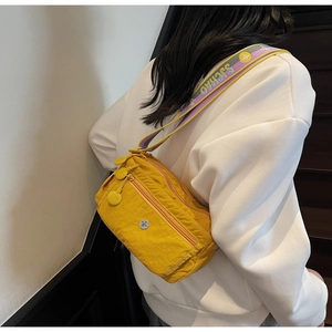 Detail view of yellow nylon crossbody bag with multi-zipper layers and jacquard strap