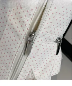 Detail von glatten silbernen Metall-Reißverschlüssen am weißen Rucksack mit rosa Punkten