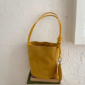 Detail of yellow matte leather bucket bag with knot shoulder strap and round coin pouch