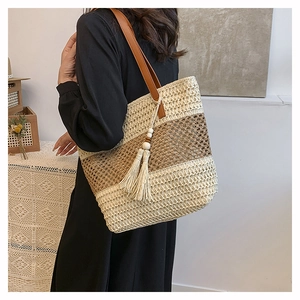 Dettaglio della borsa tote in paglia intrecciata a mano con strisce bicolori e nappine