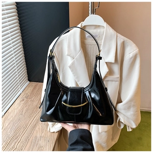 Détail du sac hobo en cuir brillant noir avec boucle dorée en croissant et bandoulière