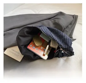 Macro view of the large capacity interior of a navy plaid crossbody bag with tablet inside