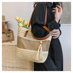 Dettaglio della borsa tote in paglia intrecciata con cuciture a contrasto e manici in pelle