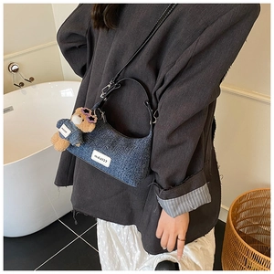 Détail du sac demi-lune en jean avec bandoulière en cuir et charm ours en denim