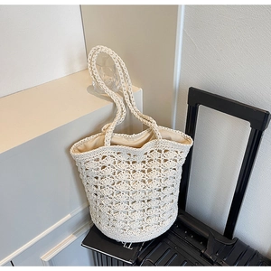Detail of hand-woven off-white straw tote bag featuring wavy openwork and fabric lining