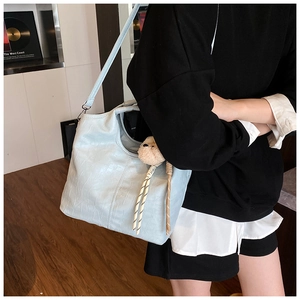 Light blue faux crocodile tote bag with plush charm shown worn over the shoulder