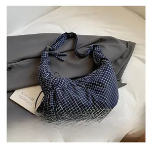 Detailed macro of dark blue plaid fabric hobo bag with pleated texture and strap