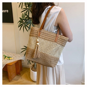 Dettaglio della borsa tote in paglia intrecciata con nappe e manici in cuoio