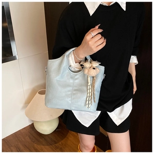 Close-up of light blue crocodile-patterned bucket bag with a cute plush bear charm