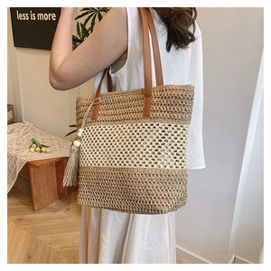 Dettaglio della borsa tote in paglia intrecciata con manici in pelle e nappa decorativa