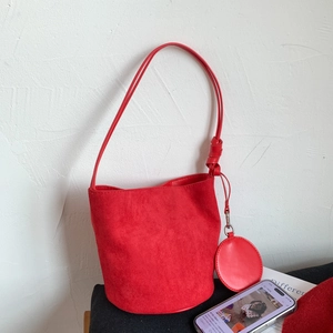 Detail of red frosted leather bucket bag with shoulder strap and mini round pouch charm
