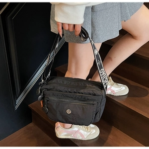 Detail of black nylon crossbody bag featuring triple zip compartments and jacquard strap