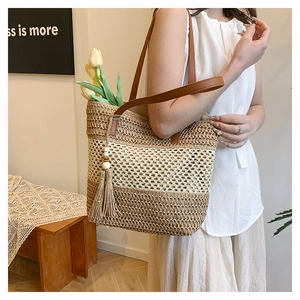 Dettaglio della borsa tote in paglia intrecciata con spalline in PU marrone e nappe