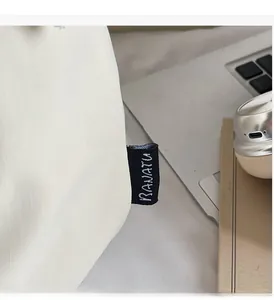 Détail du sac à main blanc en toile avec étiquette logo et texture ripstop