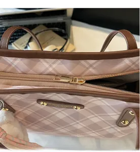 Gros plan détaillé de la fermeture éclair dorée lisse sur le sac cabas à carreaux rose