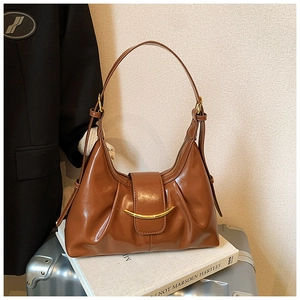 Détail du sac hobo caramel avec boucle dorée et texture plissée en cuir verni