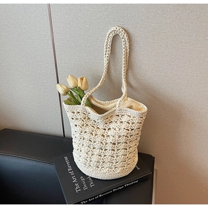 Detail view of the intricate crochet shell pattern on the cream straw bucket shoulder bag