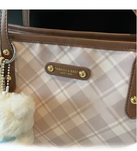 Détail du sac cabas en toile à carreaux beige avec logo en cuir brun et ours en peluche