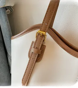 Detail of adjustable leather strap with polished gold hardware on a retro tote bag