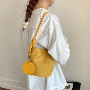 Detailed side view of yellow frosted bucket bag with a round mini coin purse charm