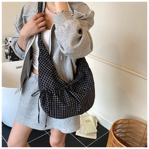 Detail of checkered canvas bag with adjustable drawstring on a minimalist interior background