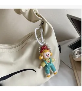Détail d'un joli charm de sac fille cartoon avec salopette verte sur un sac en toile blanc
