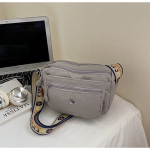 Detailed view of grey multi-pocket nylon crossbody bag with wide jacquard patterned strap