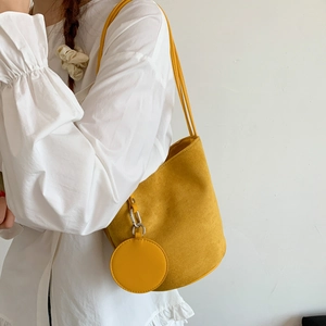 Detail of yellow frosted suede bucket bag with round charm and silver metal fastener