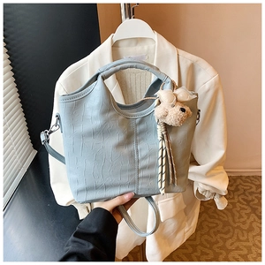 Detail of light blue crocodile embossed leather handbag featuring a cute plush bear charm