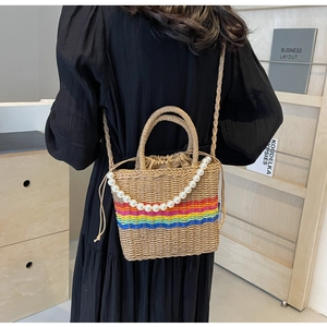 Detail of woven straw bucket bag with rainbow stripes and a decorative pearl chain