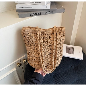 Detail of handmade straw tote bag with intricate crochet pattern and woven straps