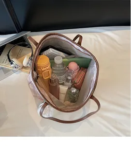 Détail montrant l'intérieur spacieux d'un sac cabas à carreaux avec effets personnels