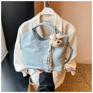 Detail of light blue crocodile texture handbag with cute plush bear charm accessory