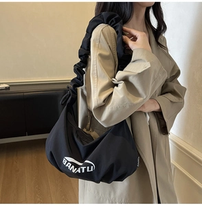 Détail de la bandoulière plissée d'un sac en nylon noir avec le logo BANATU brodé
