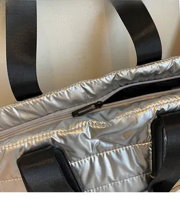 Détail du sac fourre-tout argenté matelassé avec fermeture éclair noire et poignées