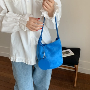 Detail of Klein blue suede bucket bag featuring a knot strap and round coin purse charm